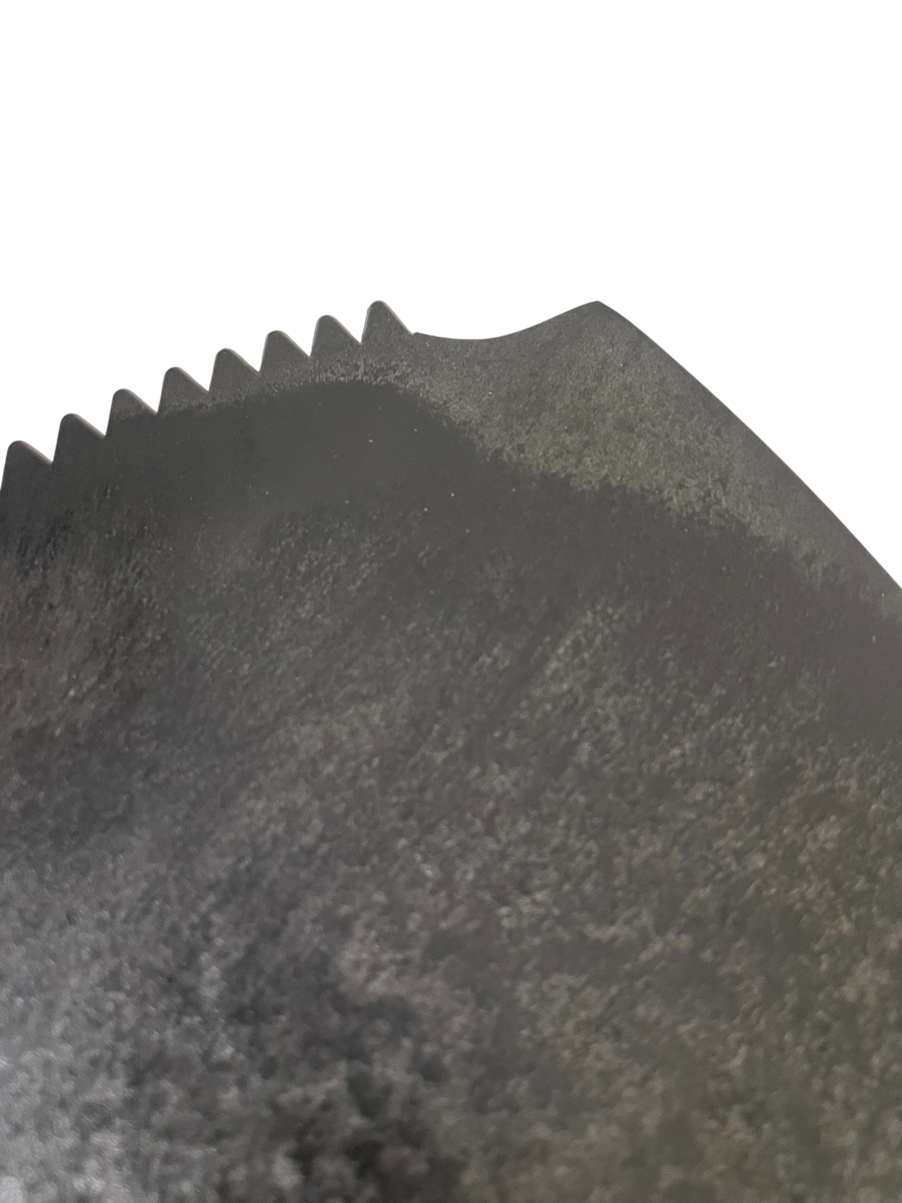 A close-up of a dark gray textured material with a serrated or scalloped edge against a plain white background.
